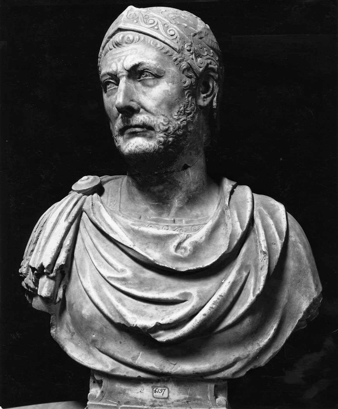 Photograph of a marble bust traditionally identified as Hannibal Barca, showing a bearded man wearing a patterned close-fitting cap, discovered at Capua and now held at the Quirinal Palace in Rome