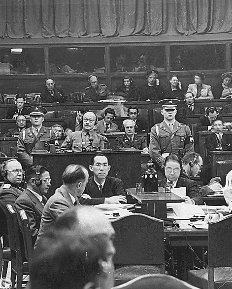 Hideki Tojo taking the stand for the first time at the International Military Tribunal for the Far East in Tokyo, surrounded by tribunal staff