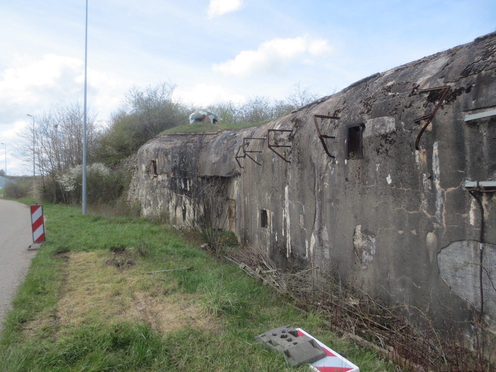 Photograph of the weathered concrete facade of Fort Casso, a Maginot Line fortress near Rohrbach-lès-Bitche, France, showing its gun embrasures and rusted anti-shell rail deflectors