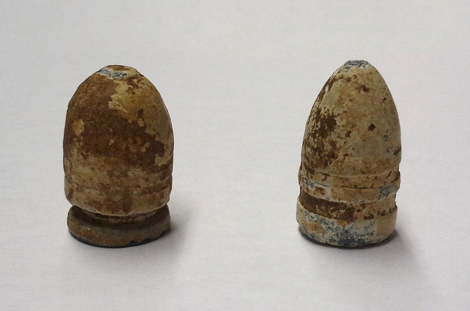A handful of Civil War-era cylindro-conoidal Minié balls with visible hollow bases, arranged on a plain surface