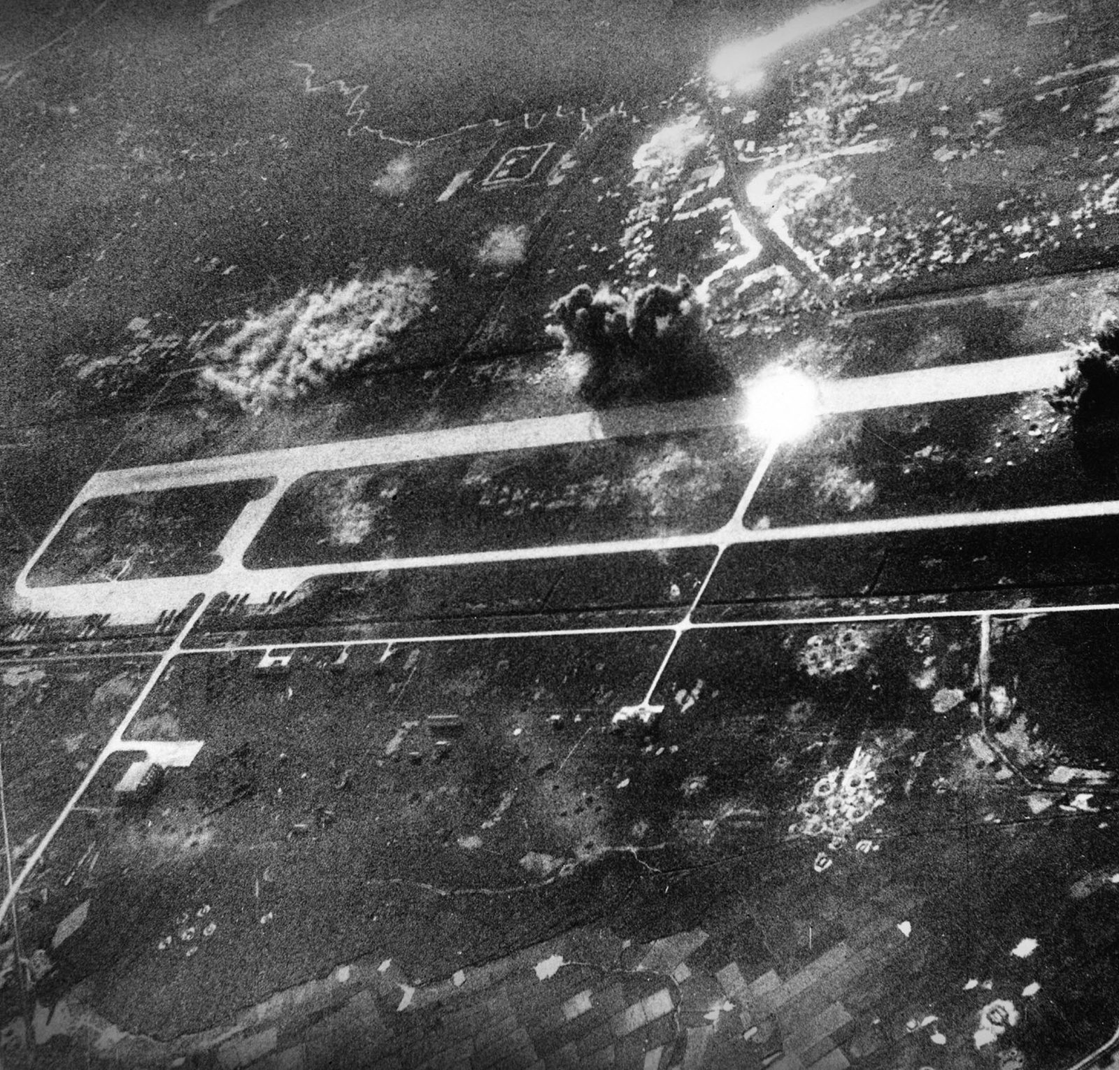 U.S. bombs strike Phuc Yen airfield northwest of Hanoi in 1967, sending up smoke and debris across the runway apron