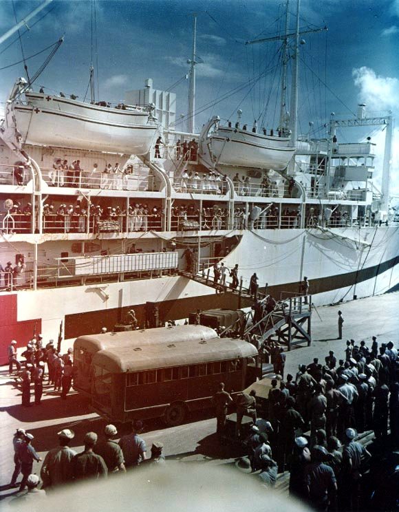 Survivors of the USS Indianapolis being carried ashore on stretchers at Guam from the hospital ship USS Tranquillity, 8 August 1945